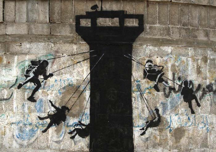 Banksy: image of kids on a merry-go-round that’s a surveillance watchtower.