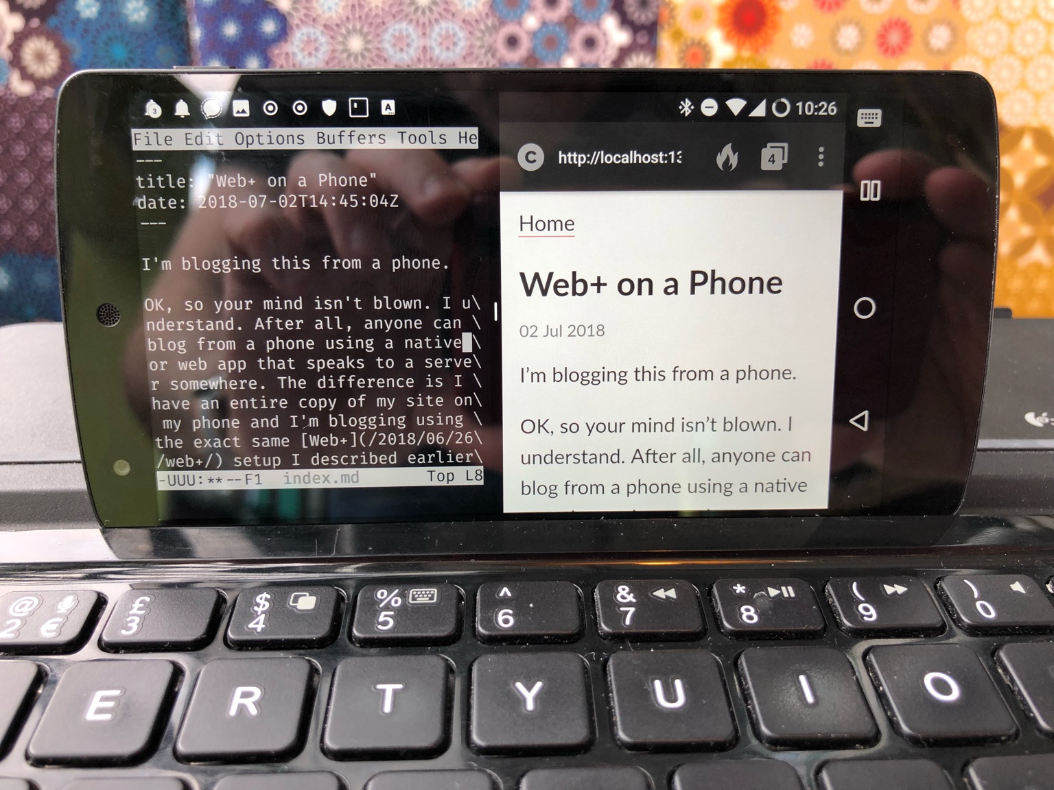 Photo of my Nexus 5 phone. The screen is split horizontally down the middle. On the left side is Emacs running with the text of this blog post showing in it. On the right side is the DuckDuckGo browser showing the rendered HTML from localhost:1313