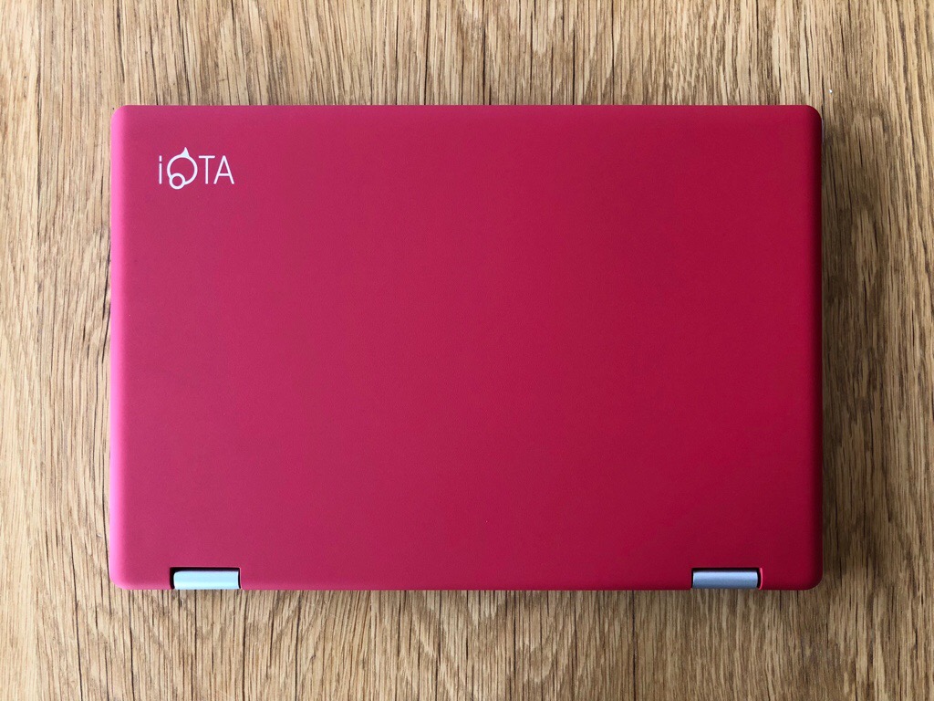 A red iOTA 360 notebook resting on a wooden table