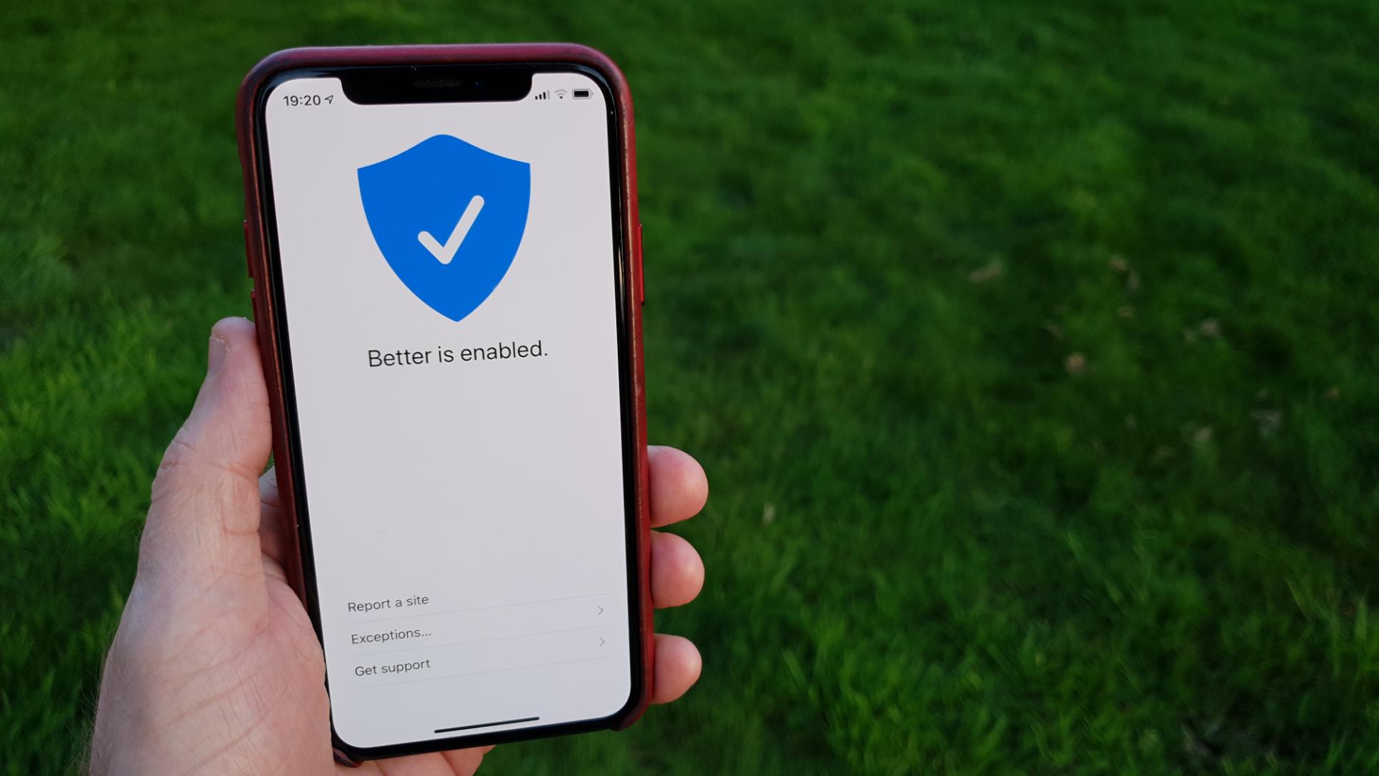 Photo of a hand, it mine, holding an iPhone X running the next bersion of Better. It is a simple, white screen with a blue shield that has a checkmark on it. Under the shield it says “Better is enabled.” On the bottom of the screen are three options: Report a site, Exceptions…, and Get support.