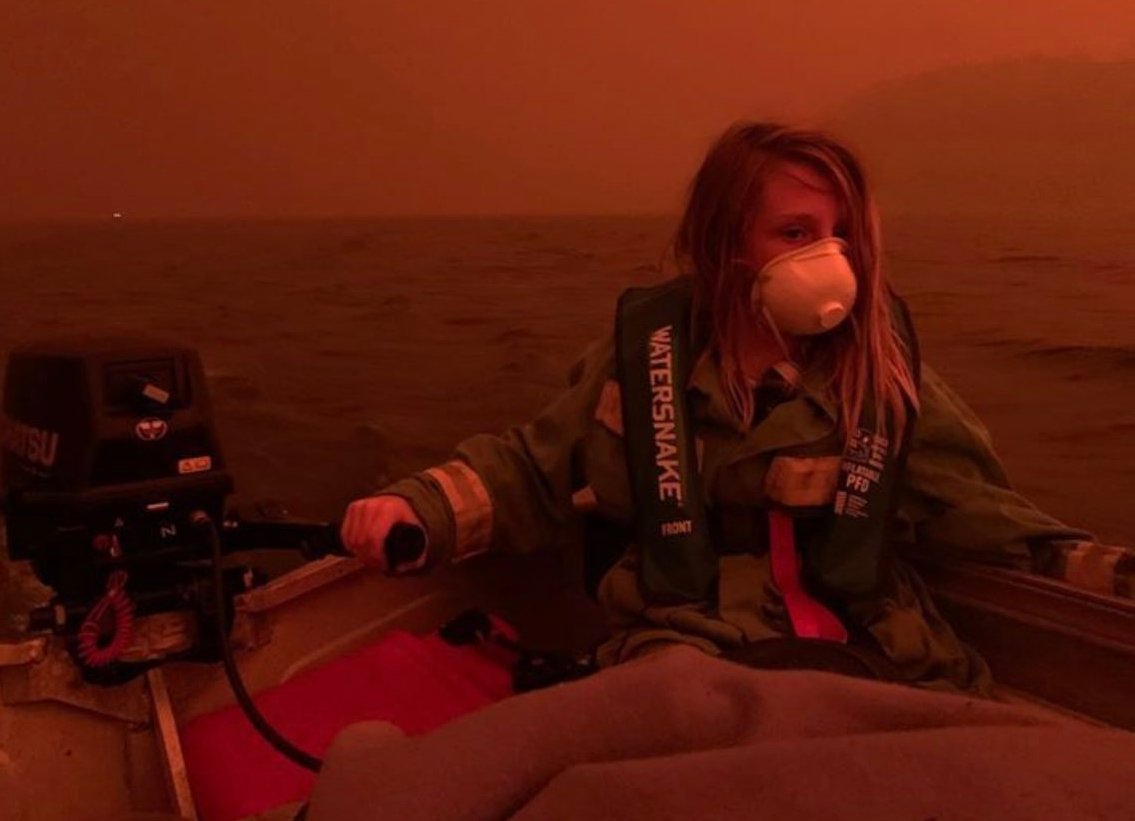 Photo of a boy driving in a boat on a lake during the fires in Australia. Photo credit: Allison Marion.