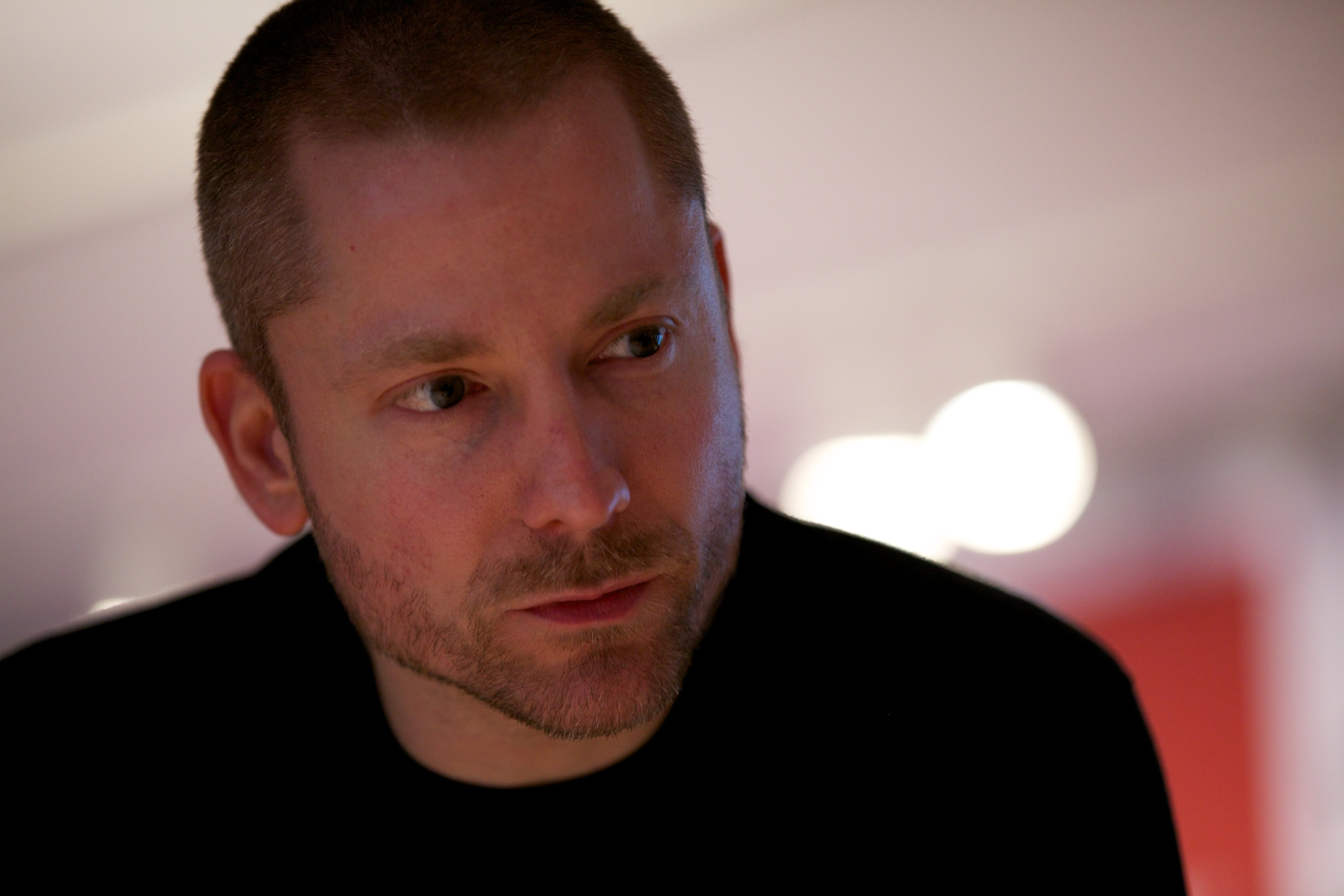 Close-up of Aral Balkan: a white-passing man with short brown hair and beard looking off-camera in-front of a bokeh background