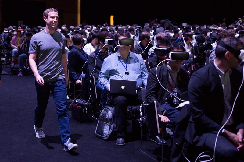 Mark Zuckerberg walks by an unsuspecting audience plugged into VR headsets.